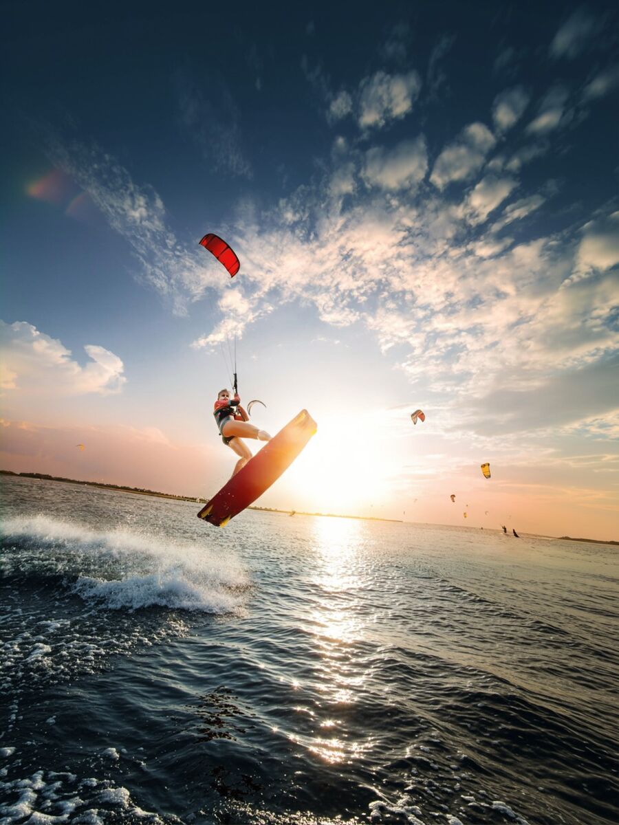 Kitesurfer jumping over the ocean at sunset